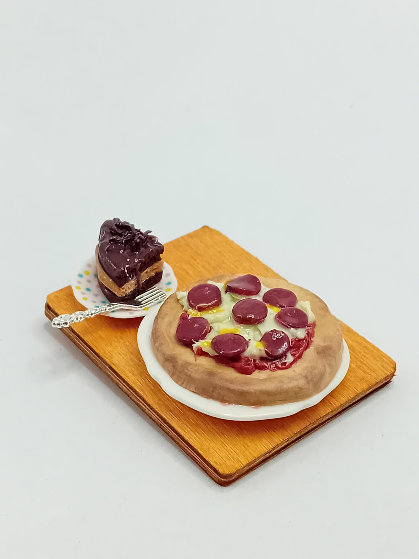 1:12 Scale pepperoni and cheese pizza made from polymer clay on a plate with a side large slice of chocolate cake and silver fork placed on a 5cm x 4cm display board.