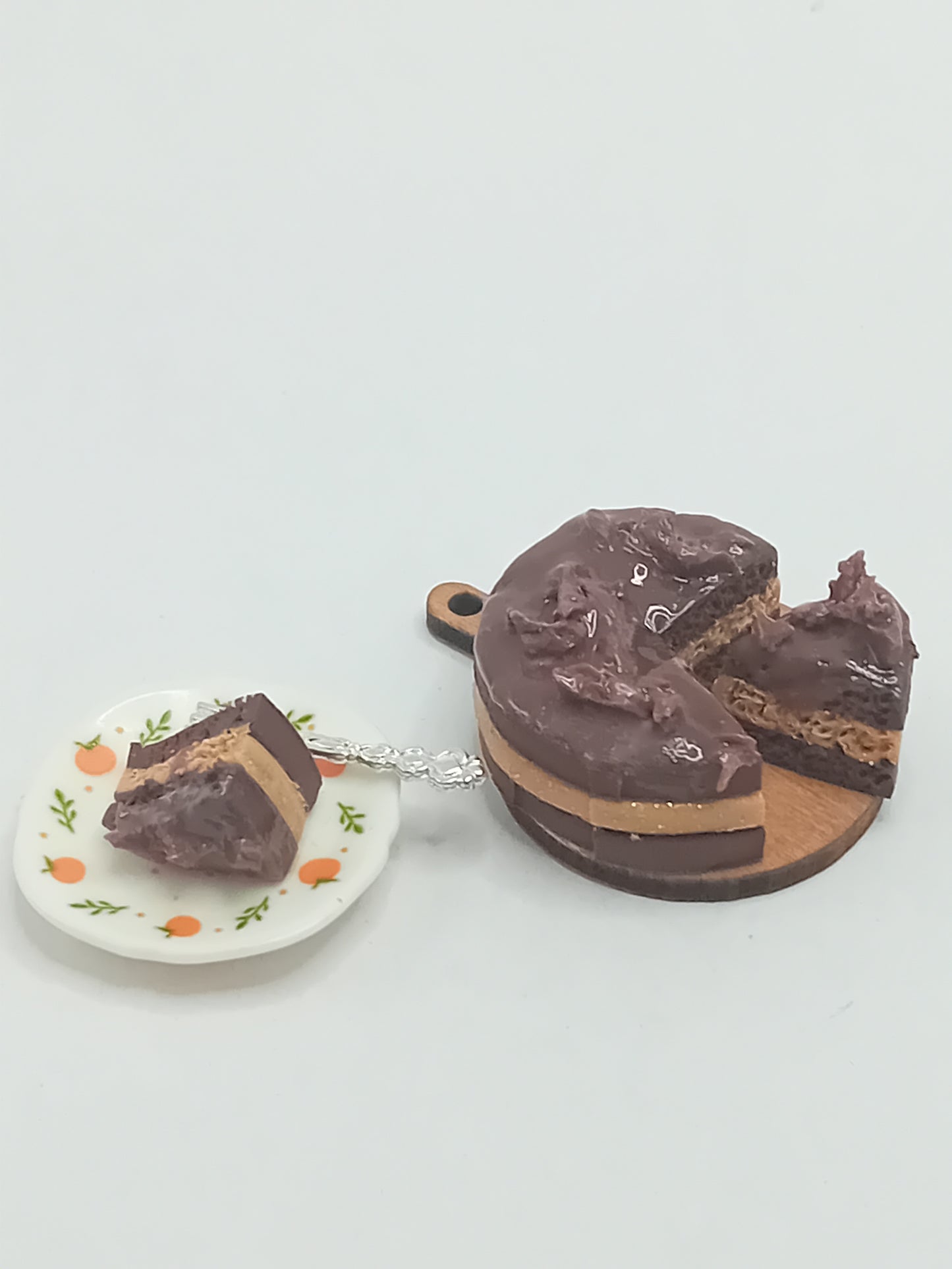 1:12 scale Chocolate Cake on a wooden cake board with a slice on a plate with a silver coloured fork.