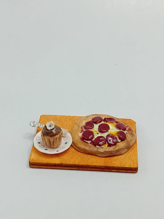 1:12 Scale pepperoni and cheese pizza made from polymer clay on a plate with a side chocolate cupcake and silver fork placed on a 5cm x 4cm display board.