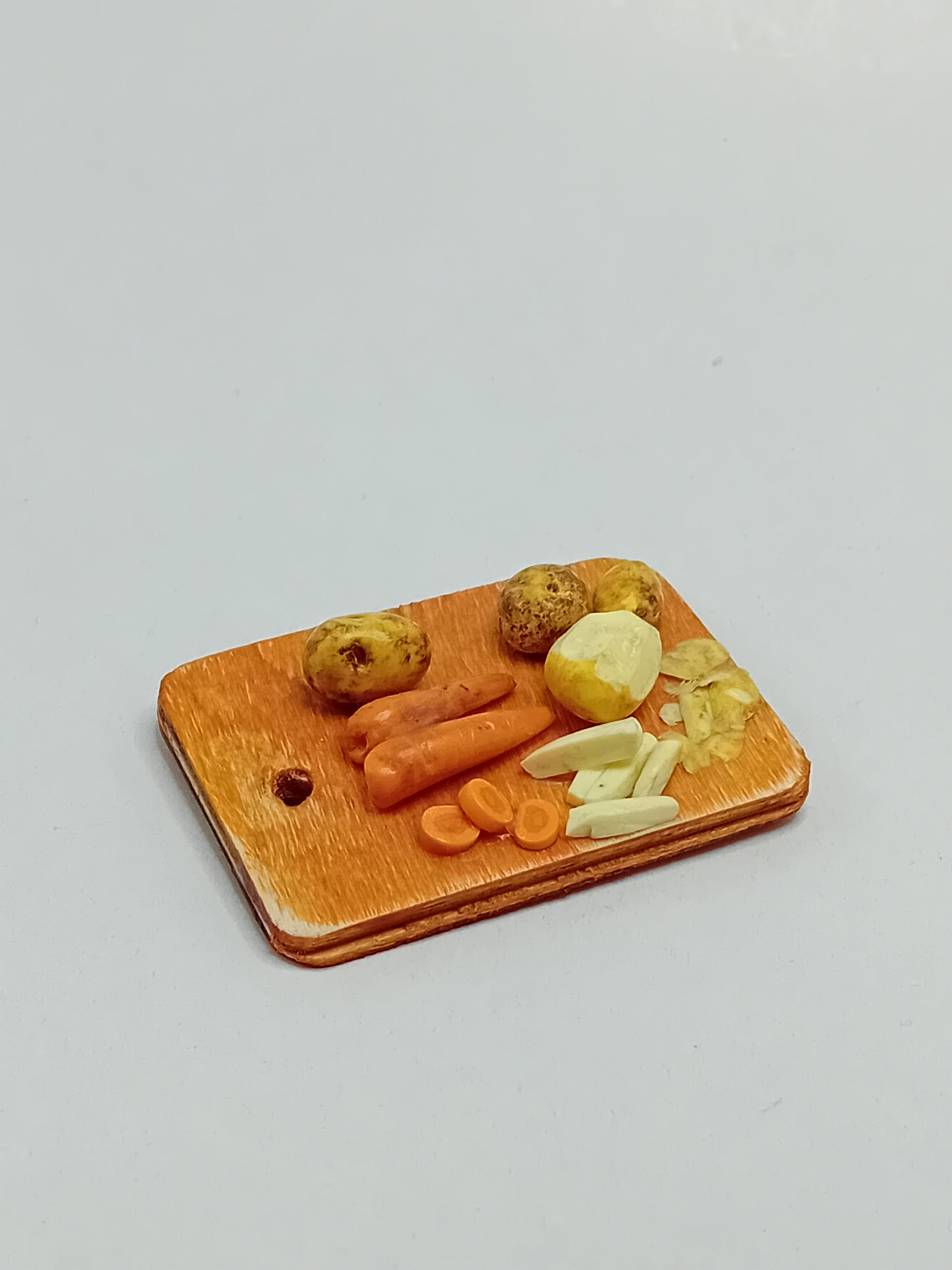 1:12 scale polymer clay Carrots, potatoes peeled and chipped on a wooden rustic farmhouse style hanging chopping board.