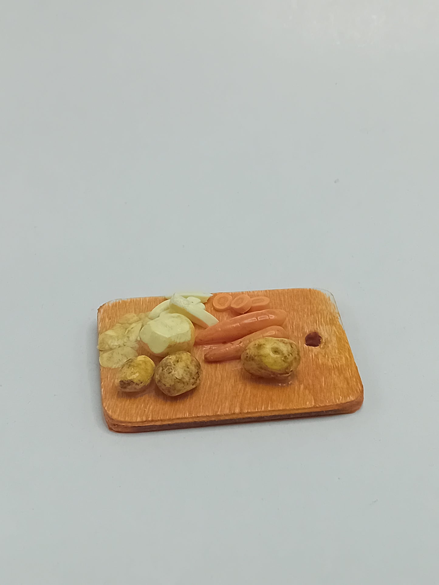 1:12 scale polymer clay Carrots, potatoes peeled and chipped on a wooden rustic farmhouse style hanging chopping board.