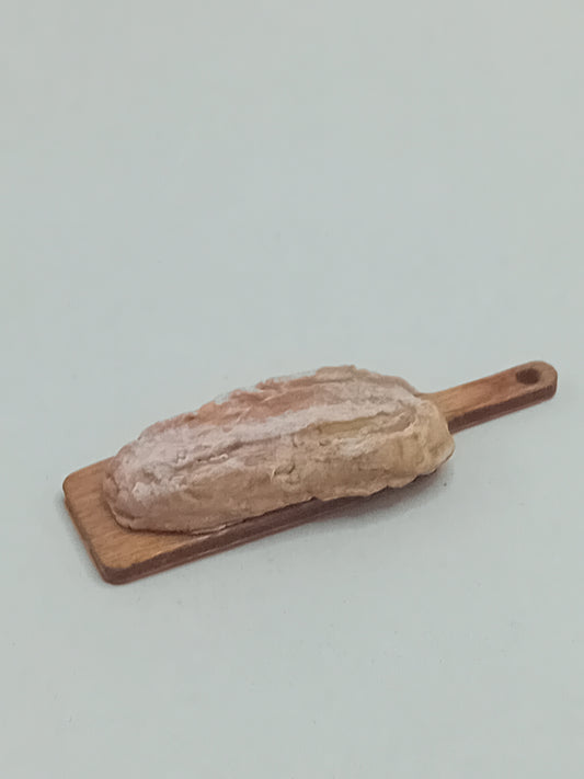 1:12 scale Polymer clay Rustic large farmhouse style sourdough loaf on a bread board.